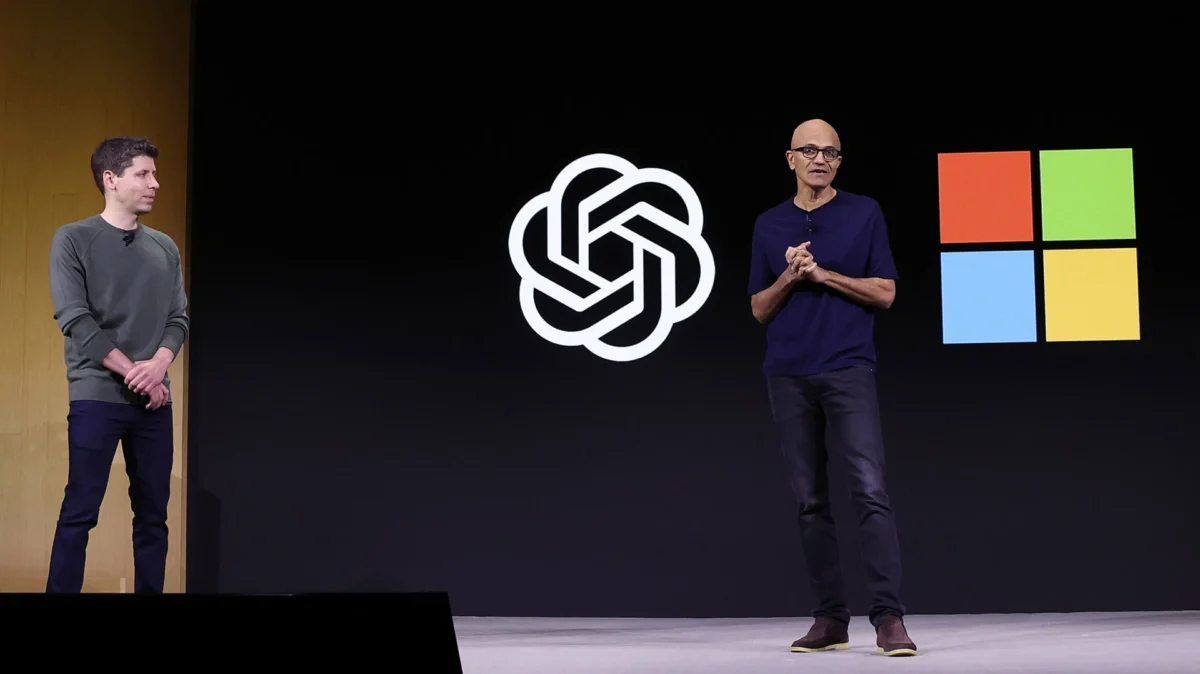 سم آلتمن (مدیرعامل OpenAI، در سمت چپ) و ساتیا نادلا (مدیرعامل مایکروسافت، در سمت راست) در حال ایستادن روی صحنه، با لوگوی OpenAI و لوگوی مایکروسافت در پس‌زمینه.