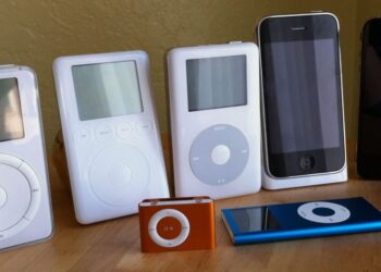 مجموعه‌ای از مدل‌های مختلف iPod و آیفون قدیمی (از جمله Classic، Mini، Nano و دو مدل آیفون) که روی یک سطح چوبی در کنار هم قرار گرفته‌اند.