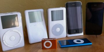 مجموعه‌ای از مدل‌های مختلف iPod و آیفون قدیمی (از جمله Classic، Mini، Nano و دو مدل آیفون) که روی یک سطح چوبی در کنار هم قرار گرفته‌اند.