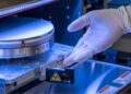تراشهٔ سیلیکونی درون دستگاه ساخت نیمههادی، هنگام نصب و بررسی معماری سهبعدی با دستکش ایمنی در محیط آزمایشگاهی.