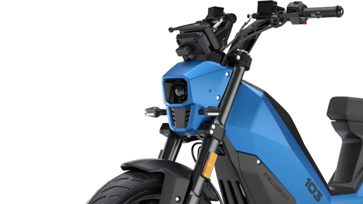 نمای نزدیک از بخش جلویی Peugeot 103 برقی با چراغ جلو، بدنه زاویهدار و سیستم تعلیق جلو.