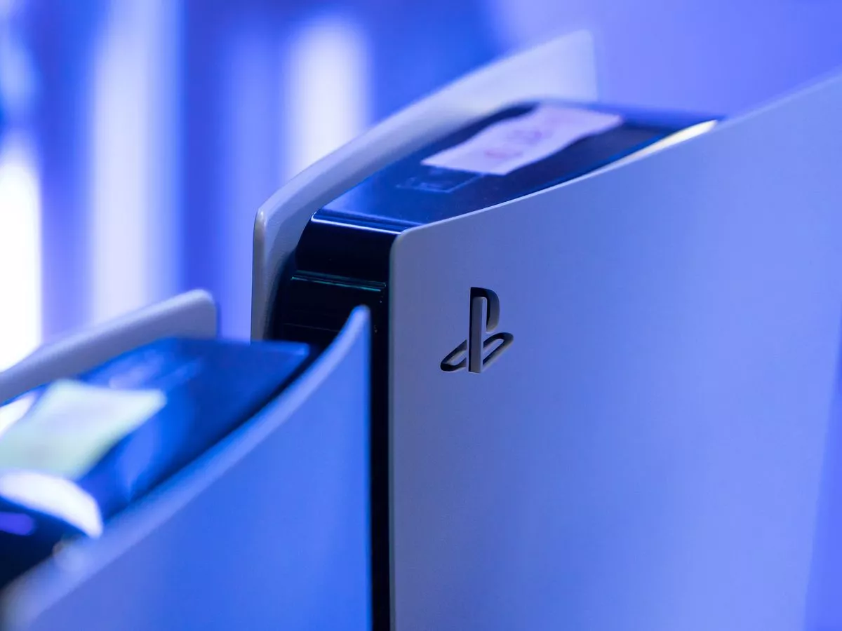 نمای نزدیک از کنسول پلی‌استیشن 5 با بدنه سفید، لوگوی PlayStation و نورپردازی آبی، تمرکز بر طراحی مدرن و جزئیات بدنه سخت‌افزار