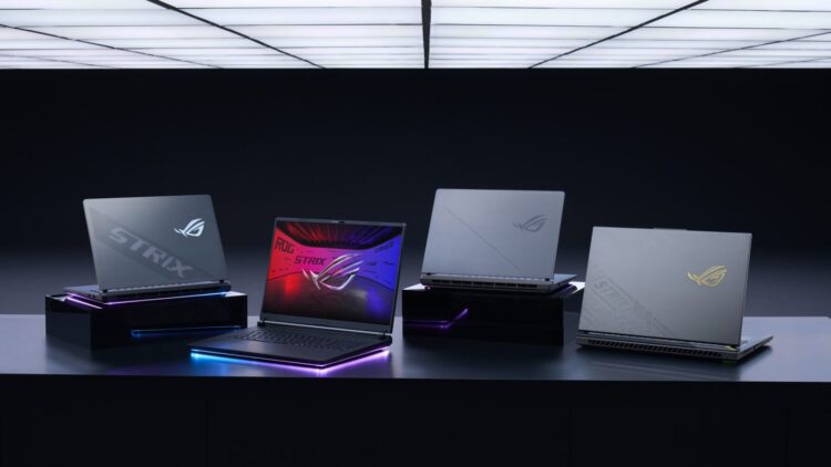نمای استودیویی از چند لپ‌تاپ ASUS ROG Strix روی استندهای مشکی با نورپردازی RGB و طراحی بدنه گیمینگ
