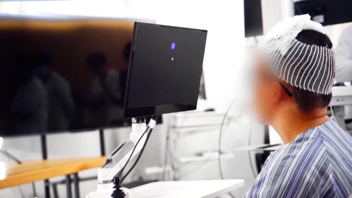 بیمار شرکت‌کننده در آزمایش رابط مغز و رایانه با کلاه ثبت سیگنال‌های مغزی در حال کنترل رایانه در محیط آزمایشگاهی