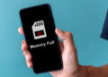نمای گوشی هوشمند در دست کاربر با پیام هشدار Memory Full روی صفحه، نماد پر شدن حافظه داخلی و مشکلات مدیریت فضای ذخیرهسازی موبایل