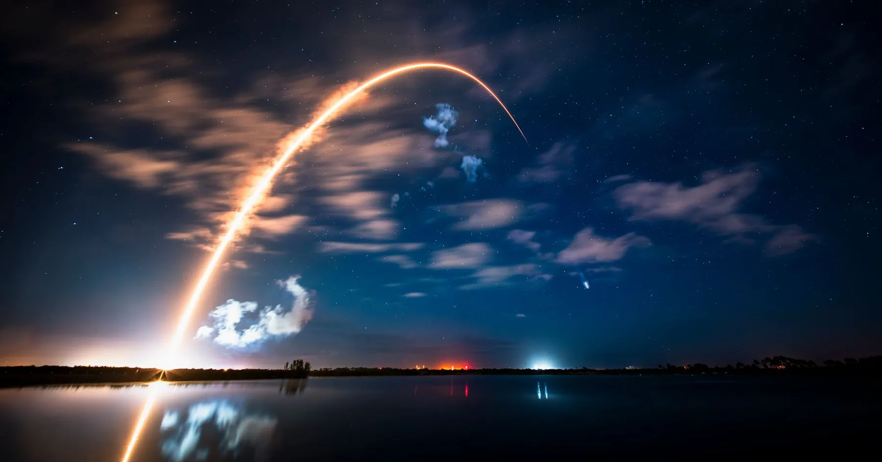 تصویر با نوردهی طولانی از رد نورانی پرتاب موشک فالکون ۹ در آسمان شب.