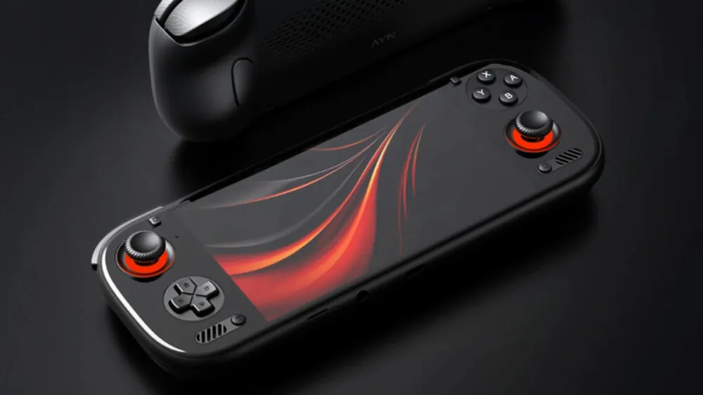 یک کنسول بازی دستی مشکی رنگ (مدل AYN Odin) با نورپردازی قرمز در اطراف جوی‌استیک‌ها و پس‌زمینه انتزاعی قرمز.