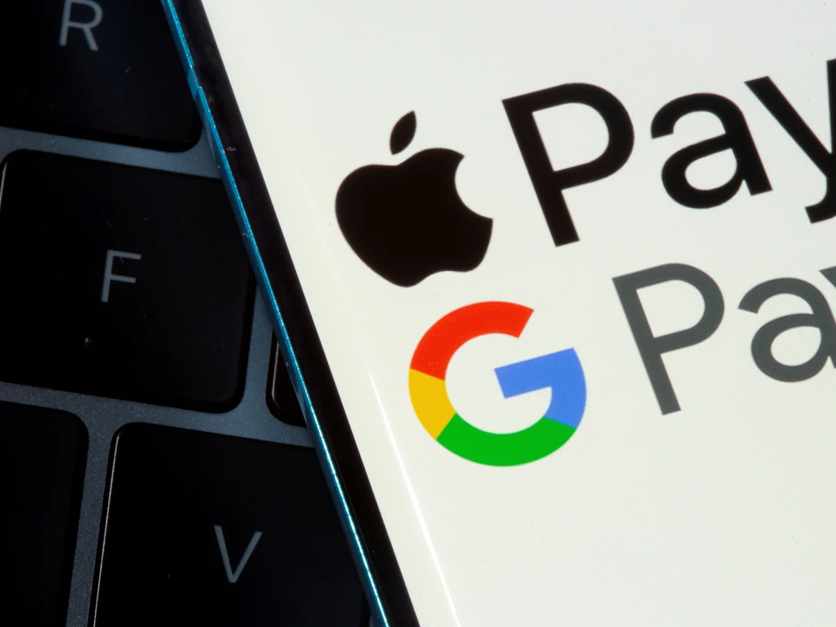 صفحه موبایلی که گزینههای پرداخت Apple Pay و Google Pay را نشان میدهد و روی کیبورد لپتاپ قرار دارد.