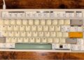 یک کیبورد مکانیکی با کلیدهای سفید، طوسی و زرد که برخی از کلیدهای ردیف بالا نصب نشده‌اند.