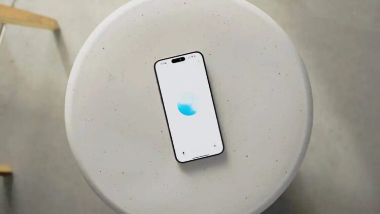 نمای بالاسری از یک گوشی هوشمند قرارگرفته روی میز گرد روشن با رابط کاربری ChatGPT Voice، نمایش انیمیشن صوتی آبی‌رنگ و اشاره به قابلیت مکالمه صوتی پیشرفته هوش مصنوعی