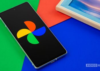 تلفن هوشمند روی پسزمینهای رنگی، که لوگوی چند رنگ Google Photos را روی صفحه نمایش خود نشان میدهد.