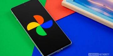 تلفن هوشمند روی پسزمینهای رنگی، که لوگوی چند رنگ Google Photos را روی صفحه نمایش خود نشان میدهد.