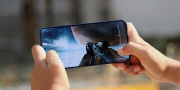 نمای نزدیک از دستهای شخصی که با گوشی هوشمند یک بازی ویدیویی فضایی را اجرا میکند.