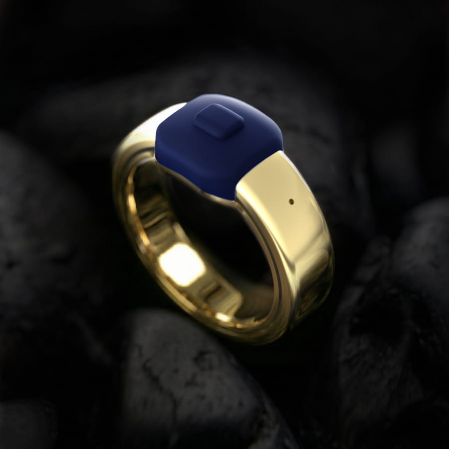 حلقه هوشمند Pebble Index طلایی با سطح براق و مرکز آبی تیره روی زمینه سنگهای مشکی