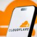 تصویر گوشی هوشمند که لوگوی Cloudflare را در پس‌زمینه‌ای نارنجی نمایش می‌دهد.