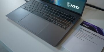 لپتاپ خاکستری MSI سری تجاری روی میز در کنار برگه مشخصات محصول.