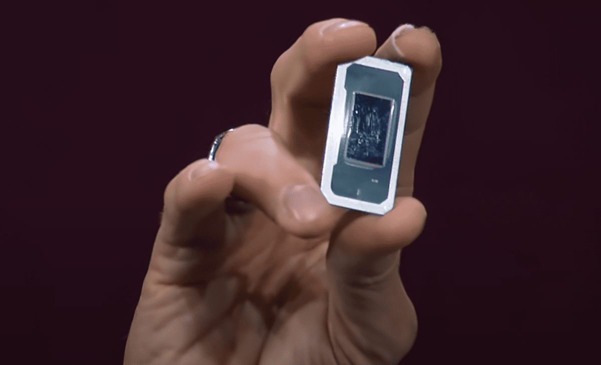 دستی که یک پردازنده کوچک و مستطیل‌شکل اینتل را در مقابل پس‌زمینه تیره نگه داشته است.