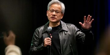 جنسن هوانگ با کاپشن چرمی مشکی معروف خود در حال صحبت کردن در یک رویداد عمومی.