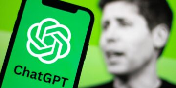 لوگوی چت‌جی‌پی‌تی روی صفحه گوشی در مقابل تصویر محو سام آلتمن.