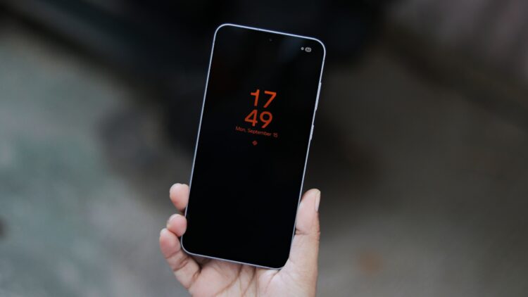 نمای نزدیک از یک گوشی هوشمند در دست با صفحه نمایش همیشه روشن (AOD).