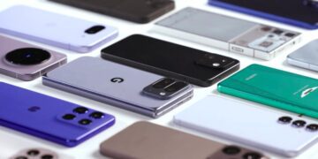 نمای نزدیک از ده‌ها گوشی هوشمند پرچمدار و میان‌رده سال ۲۰۲۵ که به صورت منظم روی میز سفید چیده شده‌اند.