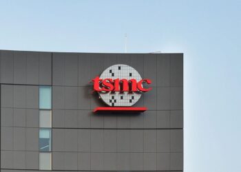 نمای بیرونی ساختمان شرکت TSMC با لوگوی قرمز رنگ این کمپانی روی بدنه خاکستری بنا.