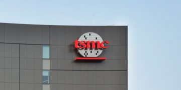 نمای بیرونی ساختمان شرکت TSMC با لوگوی قرمز رنگ این کمپانی روی بدنه خاکستری بنا.