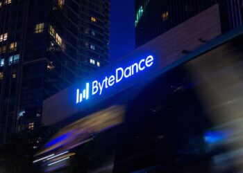 لوگوی نورانی آبیرنگ شرکت بایتدنس (ByteDance) بر روی نمای ساختمان در شب با پسزمینه آسمانخراشها.