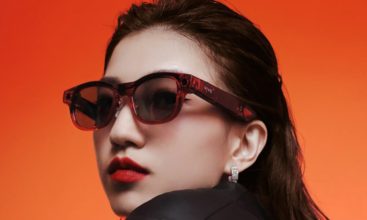 نمای نزدیک از زنی با عینک هوشمند VIVE با فریم قرمز شفاف و لنزهای تیره.