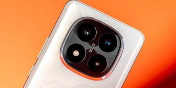 نمای نزدیک از لنزهای دوربین یک گوشی Redmi/Xiaomi بر روی پس‌زمینه نارنجی.