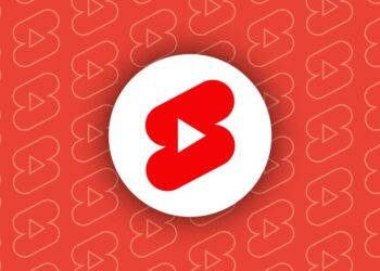 آیکون قرمز و سفید یوتیوب شورتس (YouTube Shorts) در مرکز یک پس‌زمینه قرمز با الگوهای تکراری.