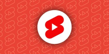 آیکون قرمز و سفید یوتیوب شورتس (YouTube Shorts) در مرکز یک پس‌زمینه قرمز با الگوهای تکراری.