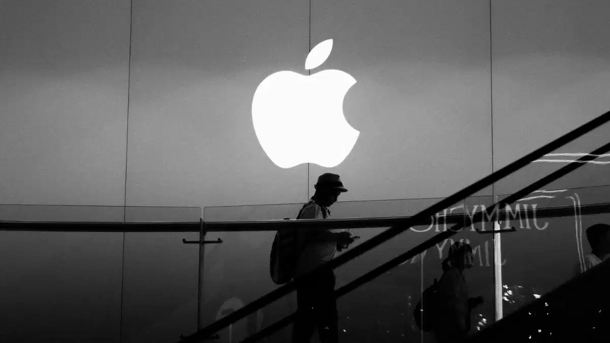 سایه یک عابر پیاده در حال عبور از جلوی لوگوی نورانی و بزرگ شرکت اپل.