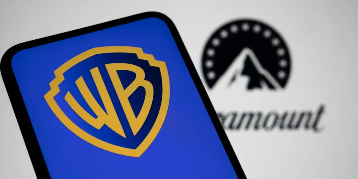 نمای نزدیک از صفحهنمایش گوشی هوشمند با نمایش لوگوی Warner Bros (WB) در رنگ آبی و زرد؛ در پسزمینه تار، لوگوی Paramount بهصورت خارج از فوکوس قابل مشاهده است.