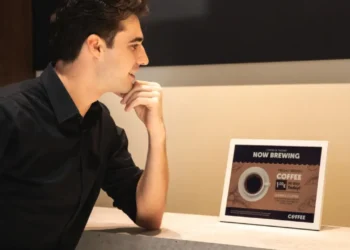 نمای محیطی از یک نمایشگر رومیزی سامسونگ روی کانتر، در حال نمایش محتوای تبلیغاتی نوشیدنی با تیتر Now Brewing Coffee؛ تأکید بر روشنایی یکنواخت، خوانایی بالا و کاربرد نمایشگر دیجیتال در فضاهای تجاری و کافیشاپ.