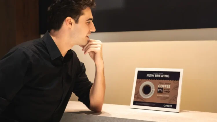 نمای محیطی از یک نمایشگر رومیزی سامسونگ روی کانتر، در حال نمایش محتوای تبلیغاتی نوشیدنی با تیتر Now Brewing Coffee؛ تأکید بر روشنایی یکنواخت، خوانایی بالا و کاربرد نمایشگر دیجیتال در فضاهای تجاری و کافی‌شاپ.