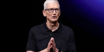 پرتره تیم کوک، مدیرعامل اپل، در حال صحبت با دستان گره خورده در برابر پس‌زمینه تیره.