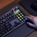 نمای محیطی از کیبورد مکانیکی Corsair Galleon 100 SD روی میز کار، نمایش کلیدهای RGB، پنل Stream Deck یکپارچه با کلیدهای LCD قابل برنامهریزی و تعامل کاربر با یکی از کلیدهای ماکرو در کنار ماوس