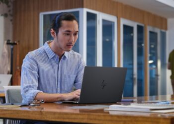 فردی در حال کار با لپتاپ جدید HP در یک فضای اداری مدرن.