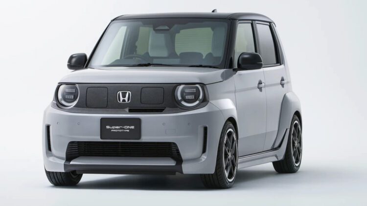 نمای سهرخ جلو خودروی برقی هوندا سوپر-وان ۲۰۲۶ با بدنهٔ خاکستری، طراحی جعبهای، چراغهای گرد LED و رینگهای اسپرت مشکی در پسزمینهٔ استودیویی سفید