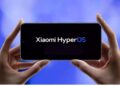 گوشی هوشمندی در دستان کاربر که لوگوی سیستم‌عامل Xiaomi HyperOS را نشان می‌دهد.