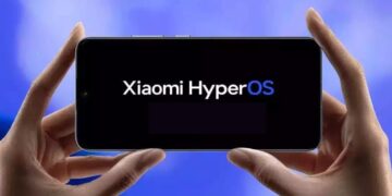 گوشی هوشمندی در دستان کاربر که لوگوی سیستمعامل Xiaomi HyperOS را نشان میدهد.