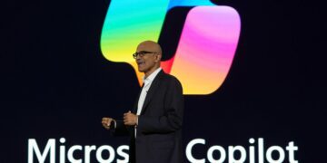 ساتیا نادلا، مدیرعامل مایکروسافت، در حال سخنرانی روی صحنه مقابل لوگوی بزرگ و رنگارنگ Microsoft Copilot.