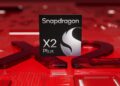 نمای نزدیک از لوگوی پردازنده Qualcomm Snapdragon X2 Plus بر روی یک مدار چاپی قرمز رنگ.