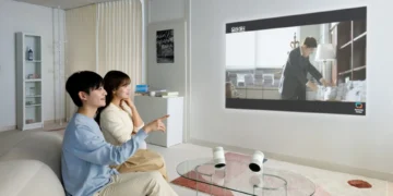 زوج جوانی که در حال تماشای تصویر بزرگ پخش شده توسط پروژکتور سامسونگ روی دیوار هستند.