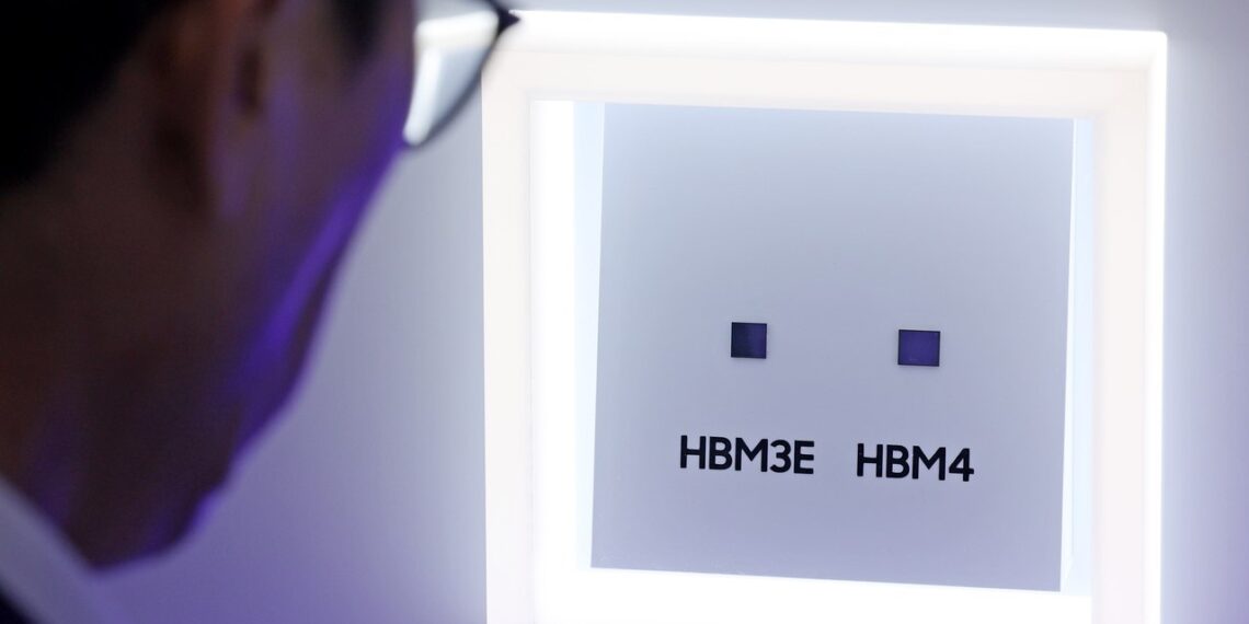نمای نزدیک از فردی که در حال مشاهده دو تراشه کوچک حافظه با برچسبهای HBM3E و HBM4 در یک محفظه نمایشگاهی روشن است.