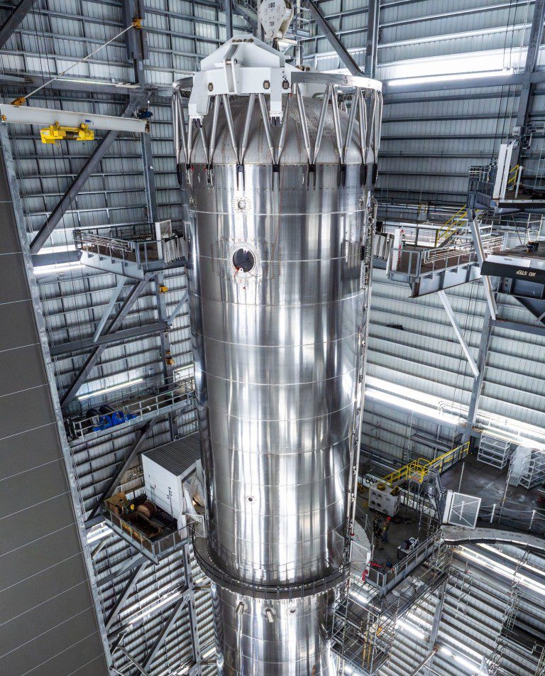 بوستر سوپر هوی استارشیپ اسپیس‌ایکس در حالت عمودی داخل آشیانه مونتاژ استاربیس با بدنه فولادی براق و سازه‌های فلزی اطراف