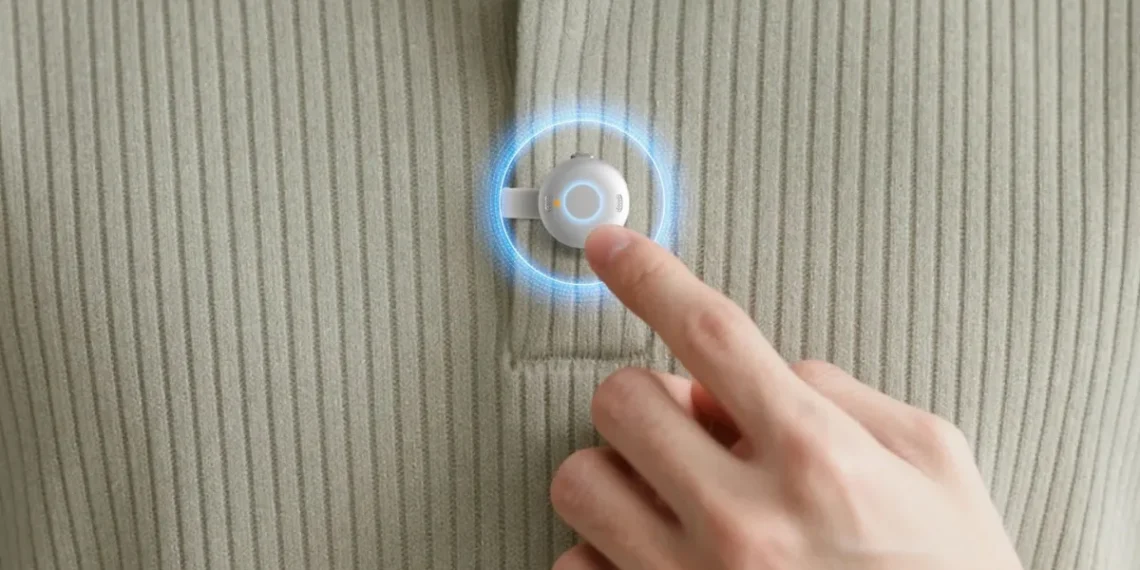 نمای نزدیک از فشار دادن دکمه یک دستگاه ضبط صدای کوچک و دایره‌ای که روی یقه لباس نصب شده است.