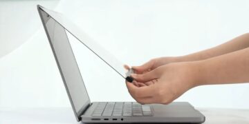 نمایی از کنار که نحوه نصب یک لایه‌ی محافظ شفاف یا اکسسوری لمسی را روی صفحه نمایش لپ‌تاپ MacBook نشان می‌دهد.