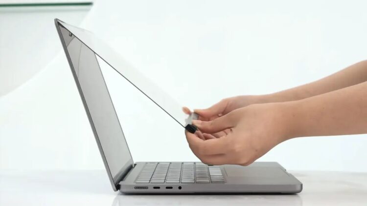 نمایی از کنار که نحوه نصب یک لایه‌ی محافظ شفاف یا اکسسوری لمسی را روی صفحه نمایش لپ‌تاپ MacBook نشان می‌دهد.